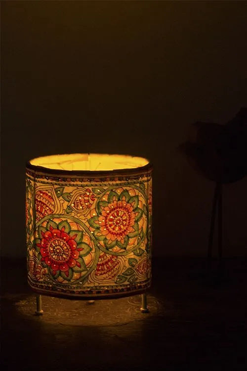 Marigold handpainted Tholu Bommalata leather table lamp lit, glowing orange and yellow petals