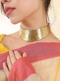 Side view of textured brass hasuli showing open back closure and curved profile
