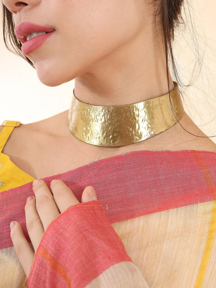 Side view of textured brass hasuli showing open back closure and curved profile