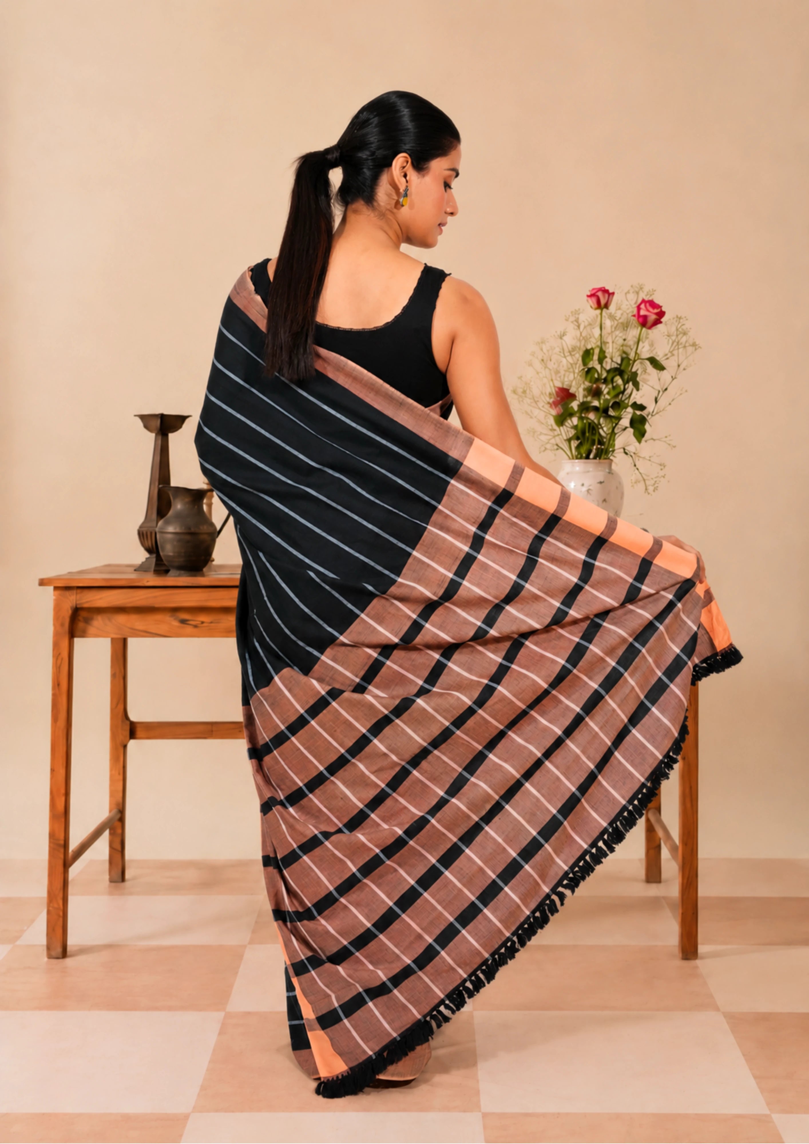 Charcoal handloom cotton saree with fine light pinstripes and a rust border, draped on a standing model, front view